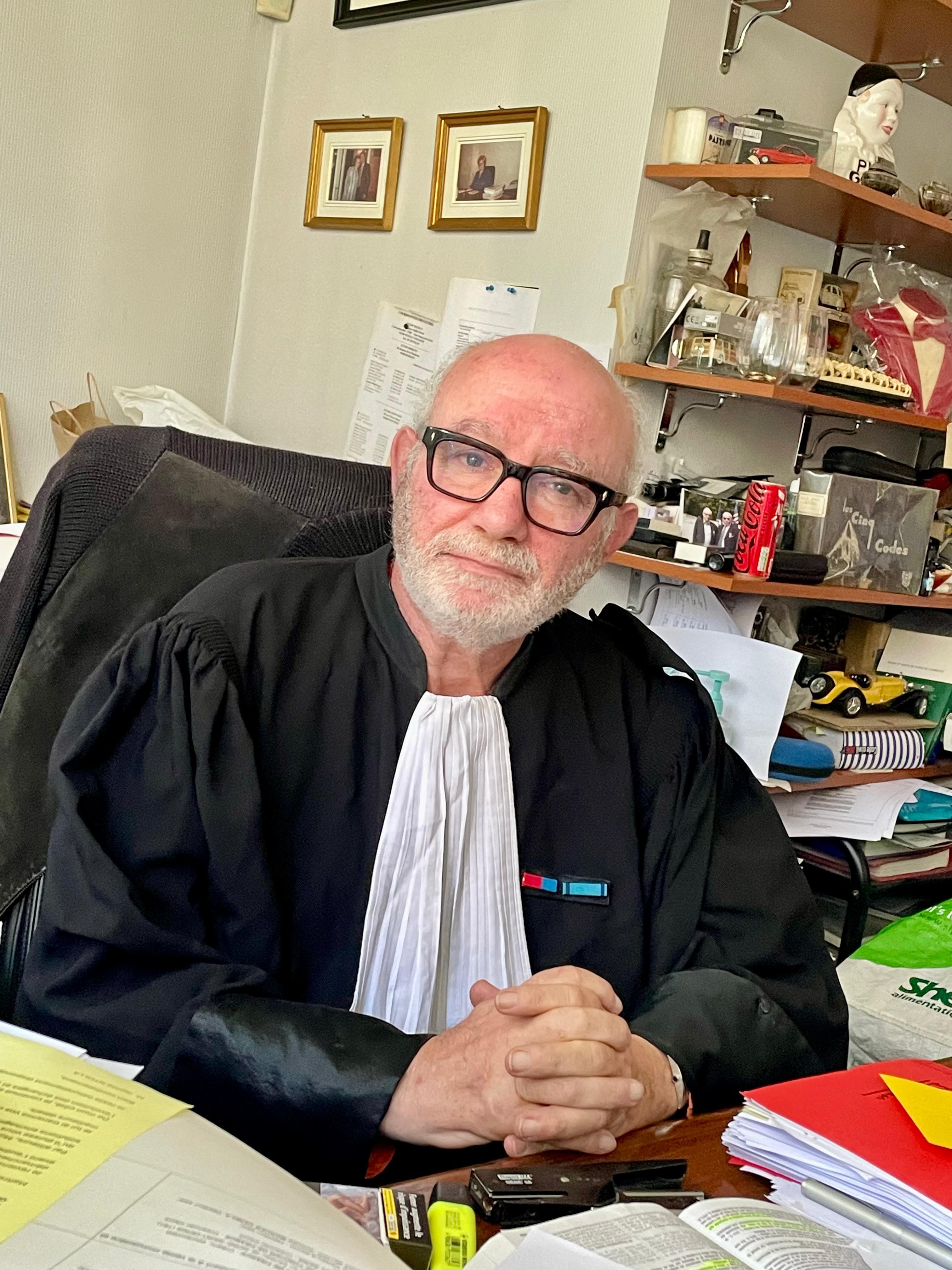 Maître Guibère en robe d'avocat dans son cabinet